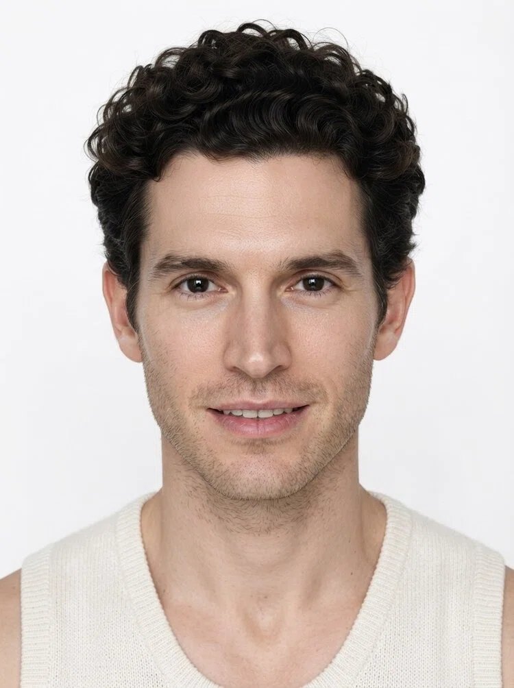 Young male fashion model with short curly dark brown hair, close-up.