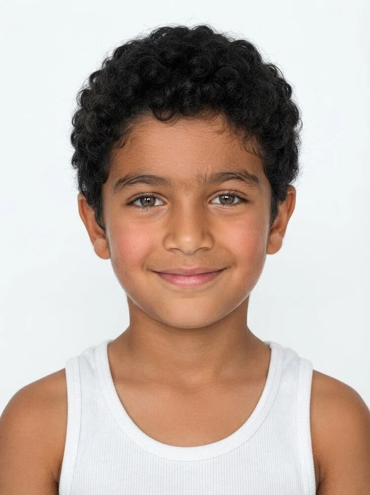 Young boy fashion model with short curly black hair, close-up.