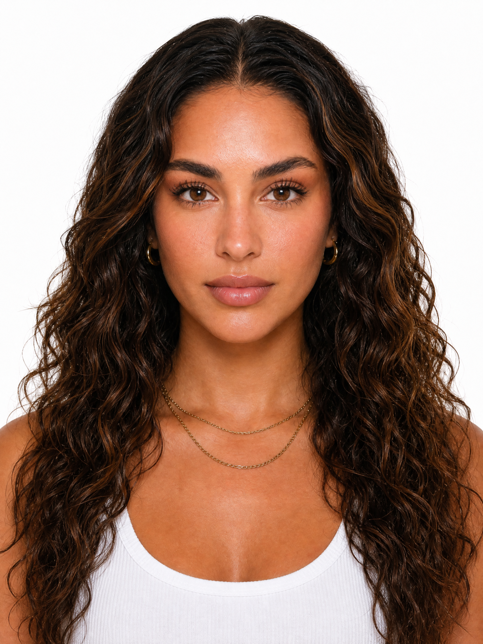 Young female fashion model with long, dark brown curly hair and gold jewelry.